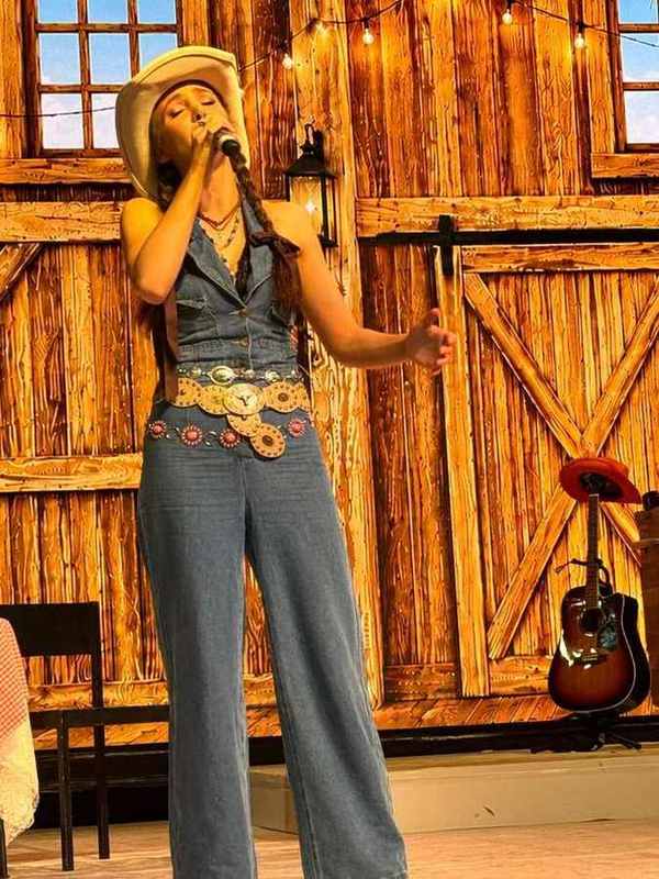A singer in a denim jumpsuit and concho belt