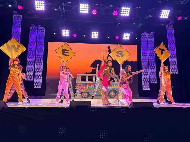 The road-trip van and WEST signs on a colourful stage
