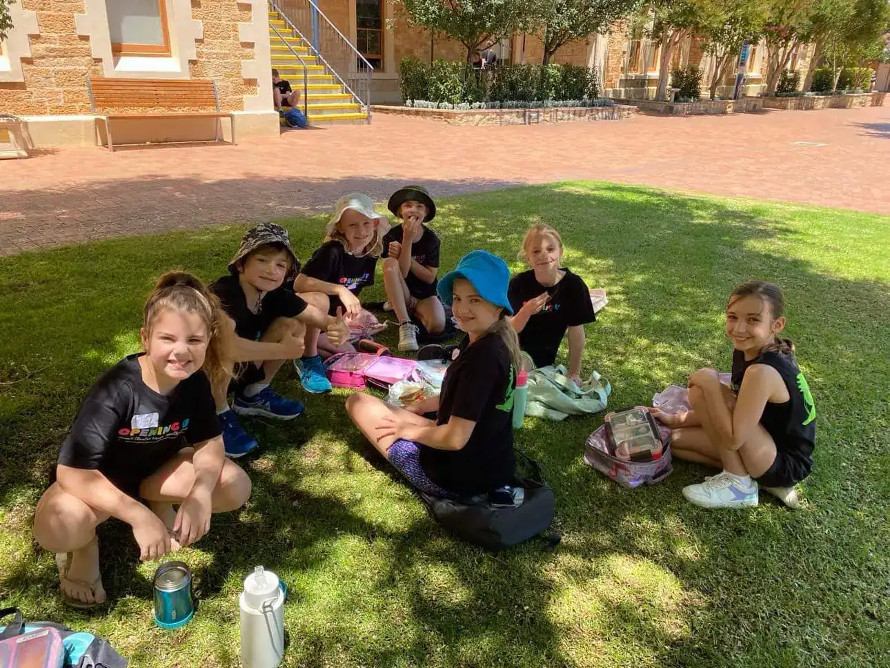 Campers sharing lunch on the grass in the sunshine