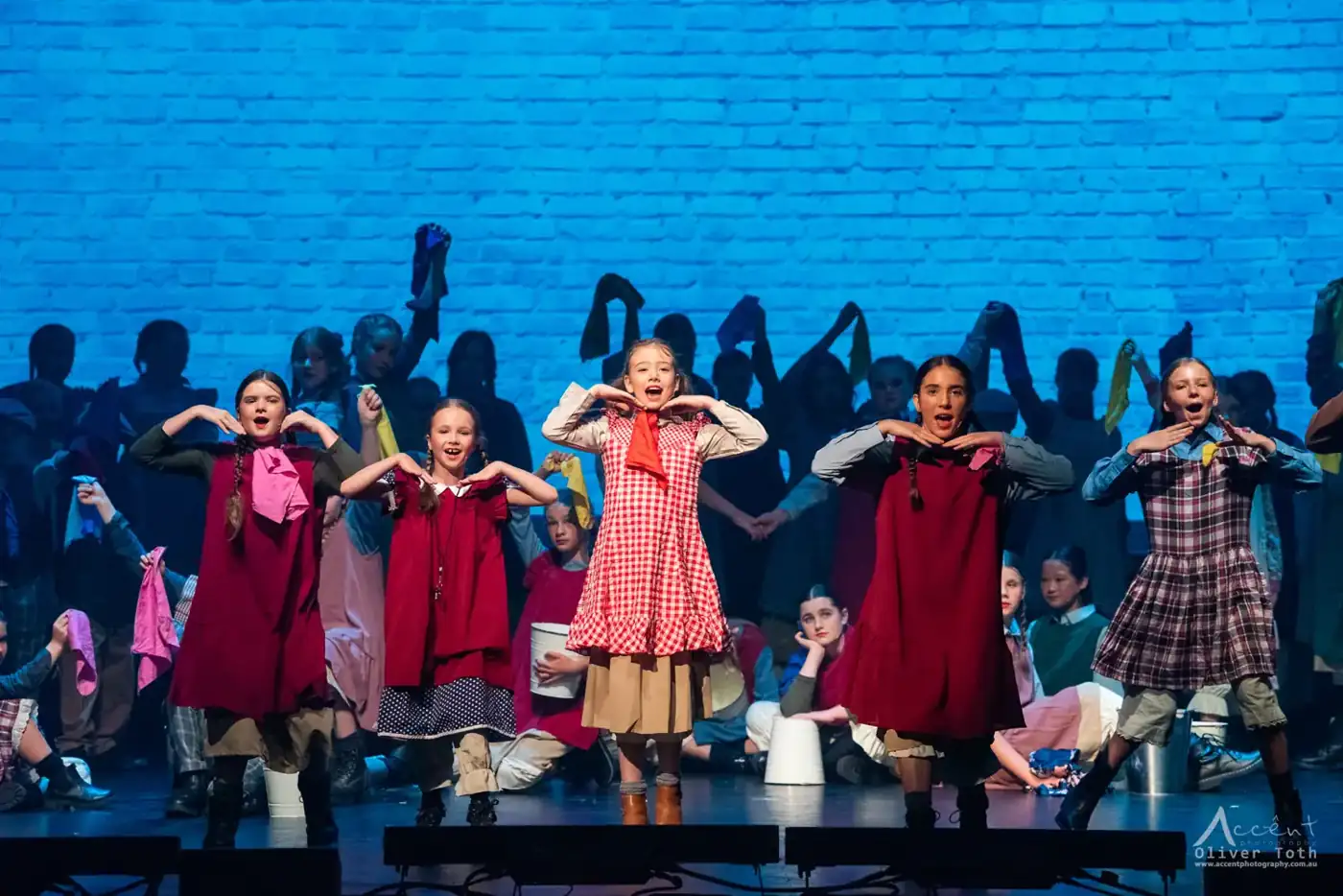 Young performers against a blue brick wall