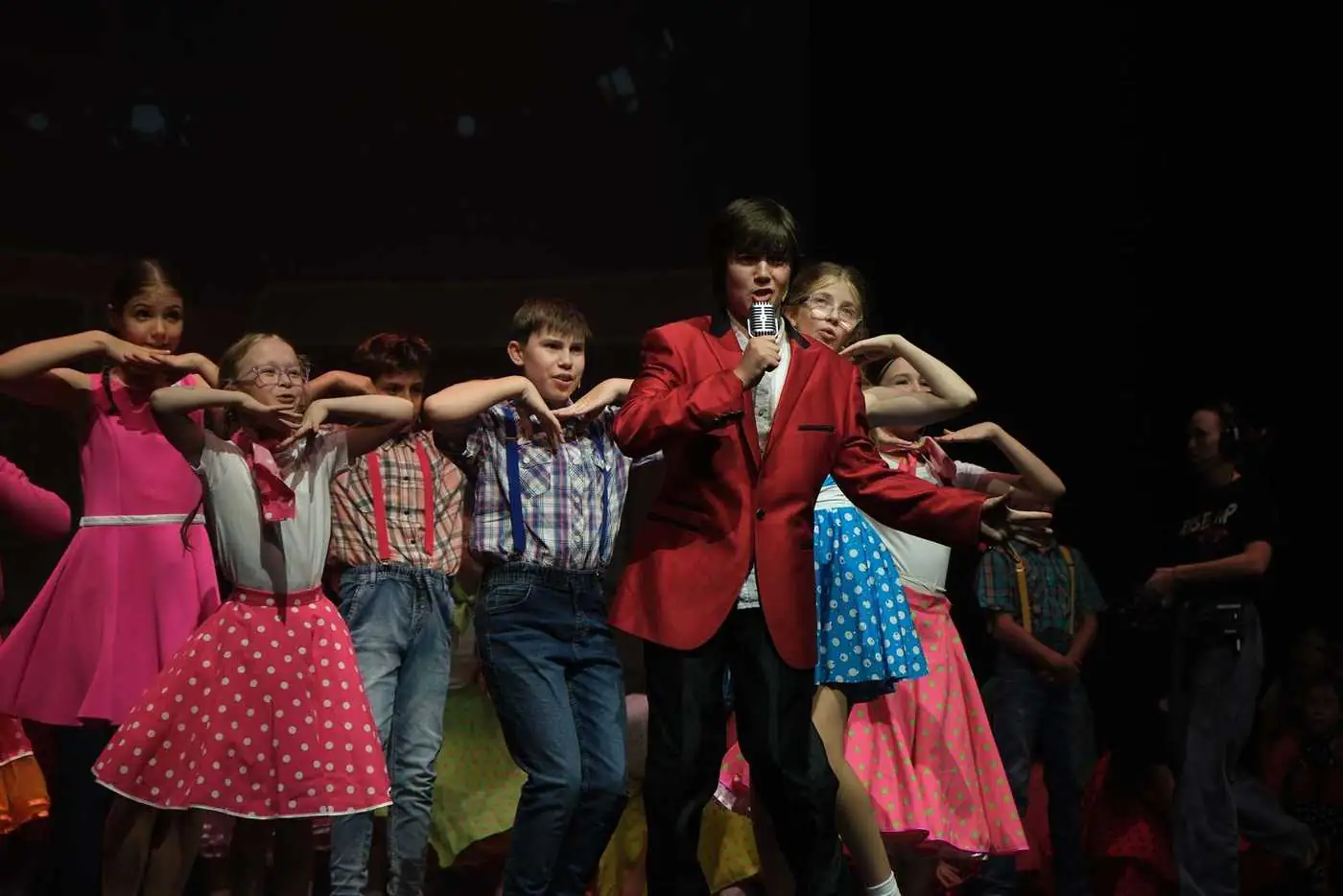 A big group of young Pelican performers in a 50s number, singing and dancing together