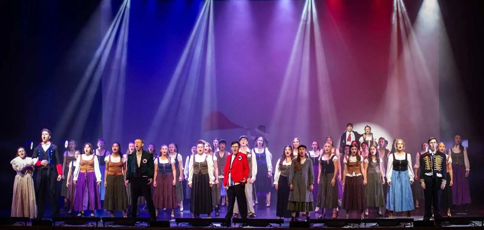 A huge Pelican company singing under red, white and blue stage lights