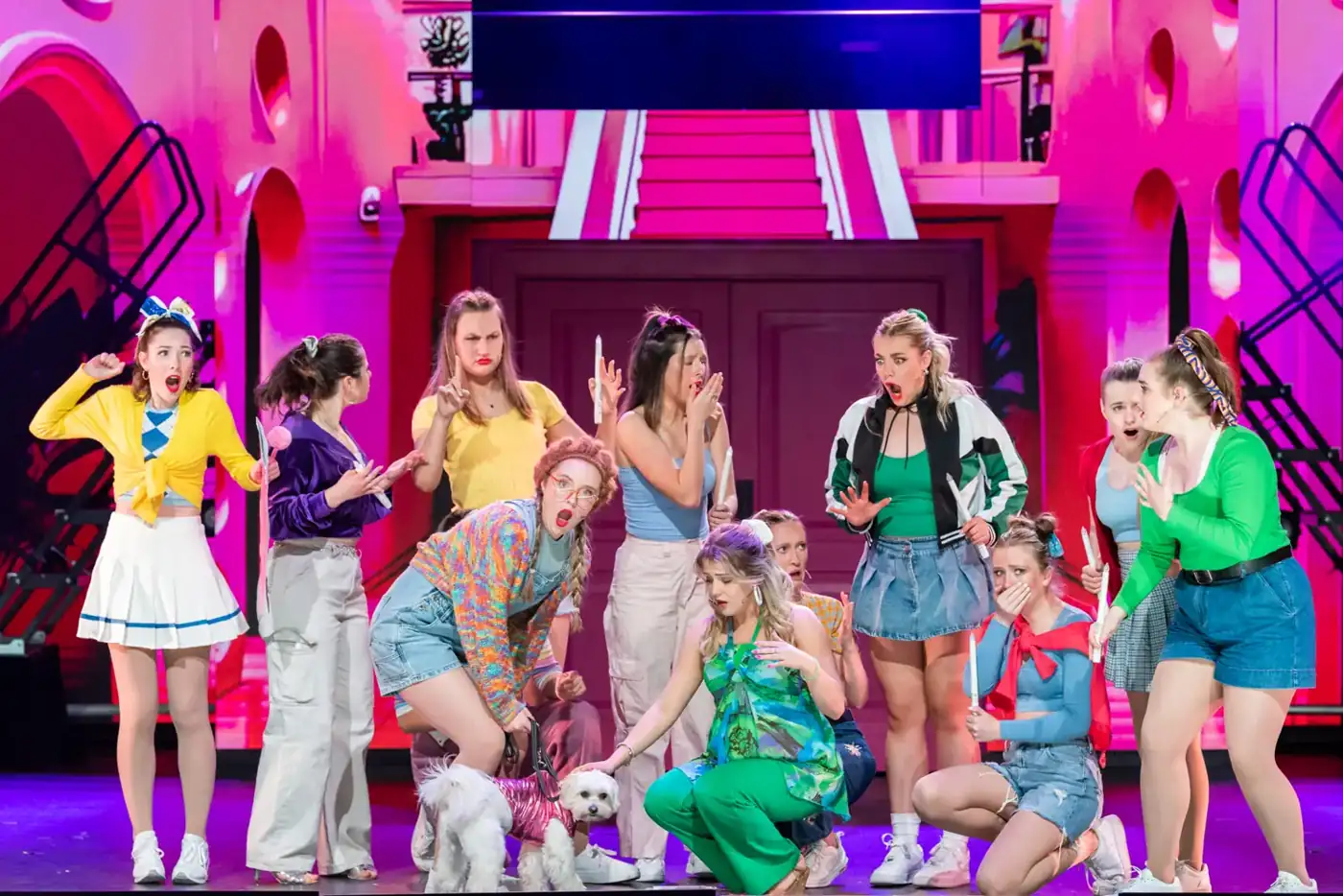 A cast in bright colours on a pink set